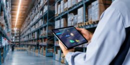 Employee with tablet analyzing numbers in freight storage warehouse