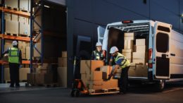 Employees at logistics company loading freight onto small delivery truck